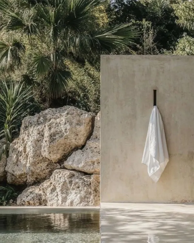Muro de concreto junto a la alberca con toalla blanca y rocas