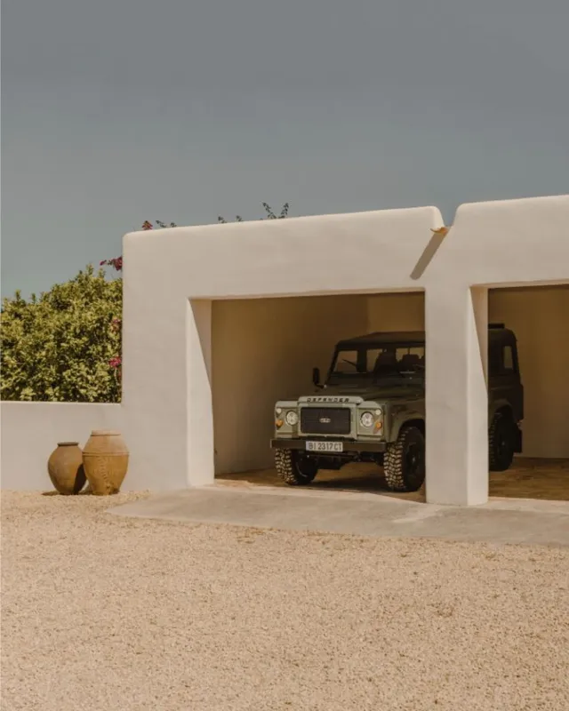 Casa blanca de estilo mediterráneo con cochera y vasijas de barro